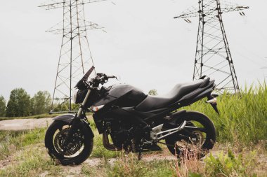 Elektrik santralinin yanında siyah spor motosikleti..