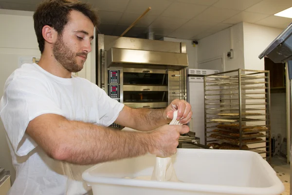 Großaufnahme eines männlichen Chefs, der den Teig auf dem Brett knetet. Brotzubereitung. Stockfoto