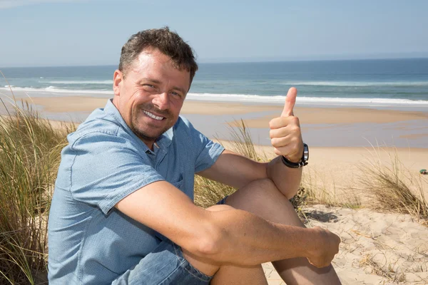 Bello felice uomo dando pollici sulla spiaggia — Foto Stock