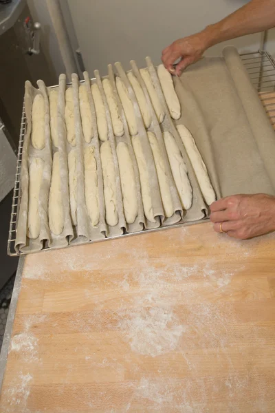 Panadero trabajando con masa sin cocer formando en rollos largos — Foto de Stock