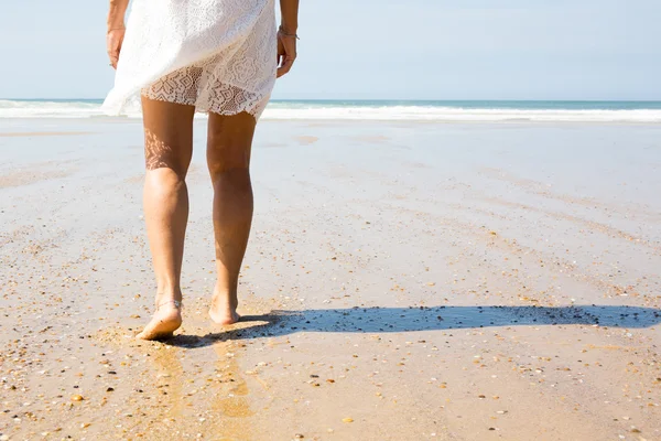 Jambe féminine marchant sur la plage dans l'océan . — Photo