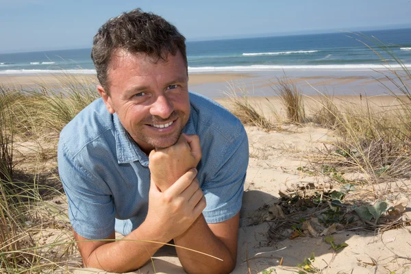 Sorridente bell'uomo che si rilassa sulla spiaggia sdraiato sulla sabbia — Foto Stock