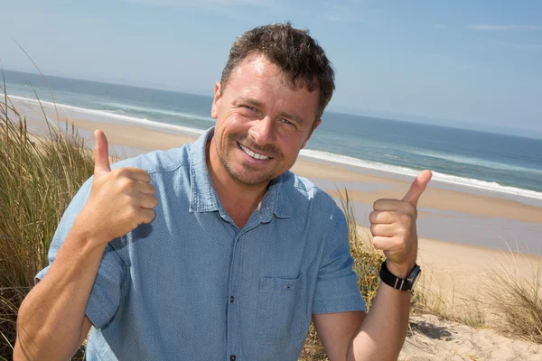 Bello felice uomo dando pollici sulla spiaggia — Foto Stock