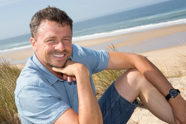 Confident and handsome man sitting on beach — Stock Photo, Image