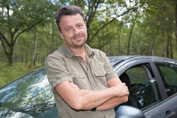 Handsome man standing in front of car smiling — Stock Photo, Image