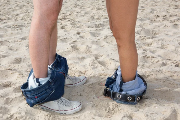 Pareja hombre y mujer pies en el amor romántico al aire libre. Piernas en jeans y zapatillas . — Foto de Stock