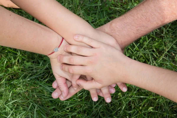 Familie handen boven elkaar met gras achtergrond — Stockfoto