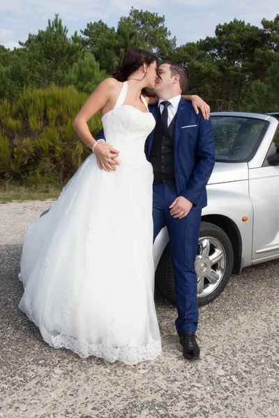 Precioso lindo novio y novia en un coche convertible gris posando — Foto de Stock