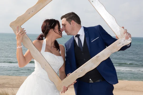 Krásné svatební pár hledá prostřednictvím rámečku obrázku — Stock fotografie