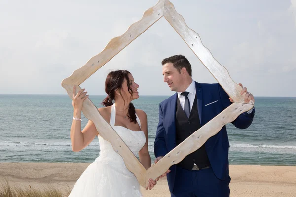 Bella coppia di nozze guardando attraverso una cornice — Foto Stock