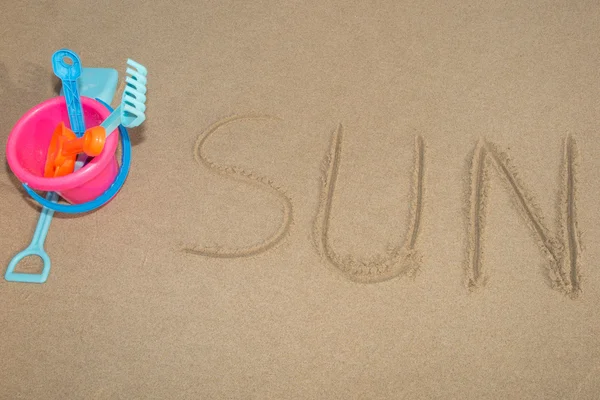 समुद्र तट की रेत पर लिखा गया शब्द "सूर्य" — स्टॉक फ़ोटो, इमेज