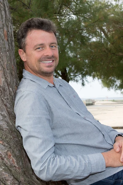 Beau homme relaxant Dans la campagne appuyé contre l'arbre — Photo