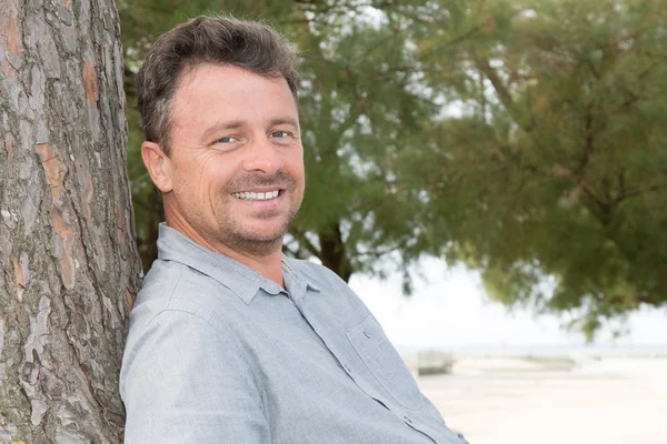 Homme joyeux relaxant Dans la campagne appuyé contre l'arbre — Photo