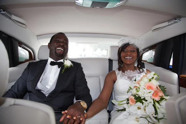 Красива молода пара щасливо посміхається в день весілля, сидячи в лімузині . — стокове фото