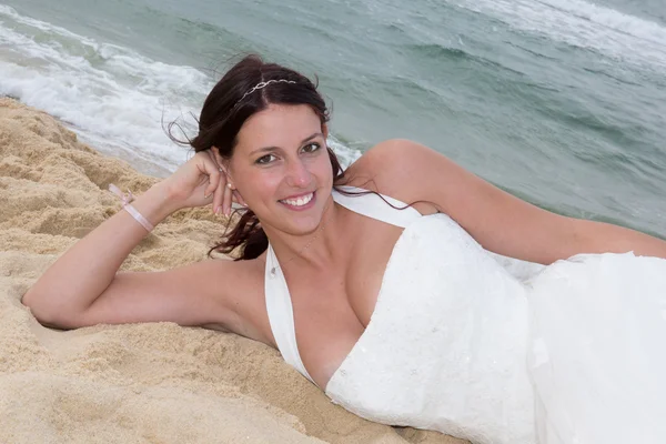 Glückliche Braut auf dem Sand im Meer liegend — Stockfoto