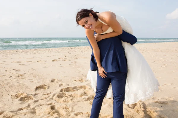 Recién casados compartiendo un momento romántico y divertido en la playa — Foto de Stock