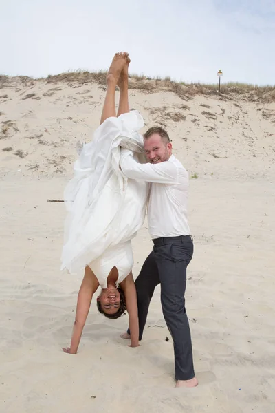 Пара на пляже в свадебном платье веселятся — стоковое фото