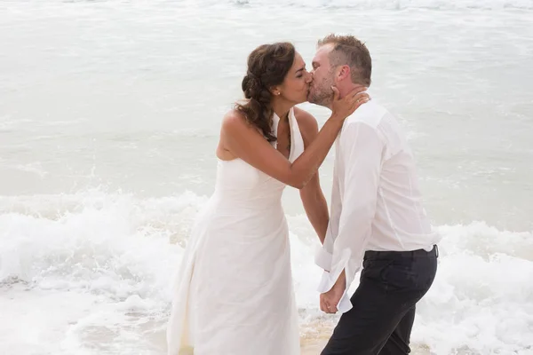 Couple marié joyeux baisers debout sur la plage — Photo