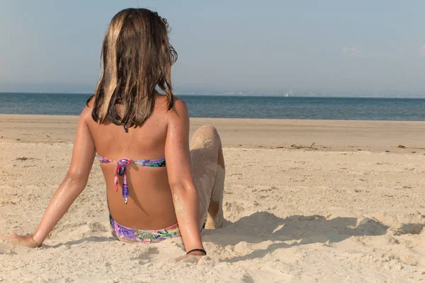 Baksidan på långhåriga flicka i bikini på stranden — Stockfoto