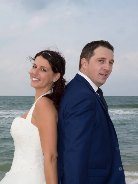 Pár na pláži ve svatebních šatech zády k sobě — Stock fotografie