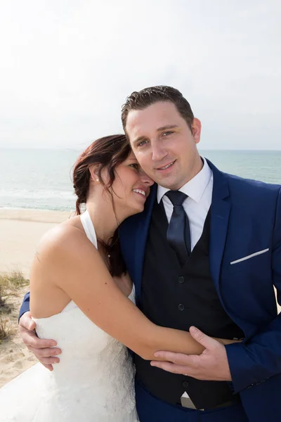 Sorridente coppia sposata in piedi sulla spiaggia — Foto Stock