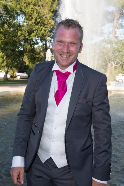 Blonder sexy Mann im Smoking und rosa Krawatte posiert — Stockfoto