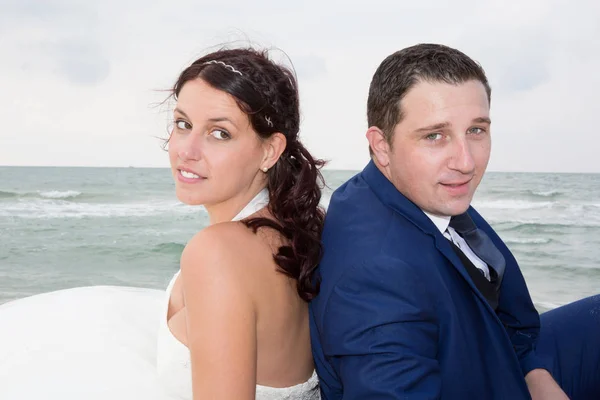 Пара на пляже в свадебном платье спиной к спине — стоковое фото