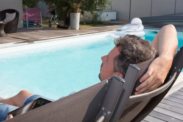 Hombre guapo relajarse en una silla cerca de la piscina — Foto de Stock