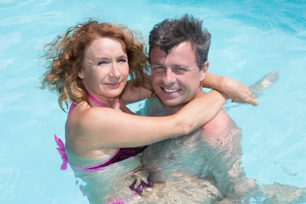 Happy and attractive couple enjoying holidays in the pool — Stock Photo, Image