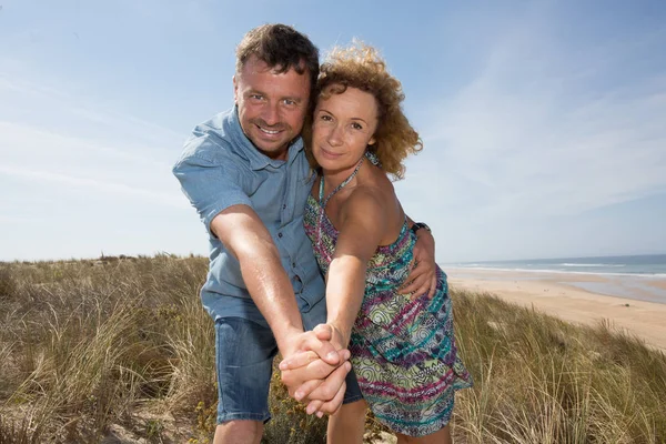 男と女のカップルがビーチで日差しの中で微笑む — ストック写真