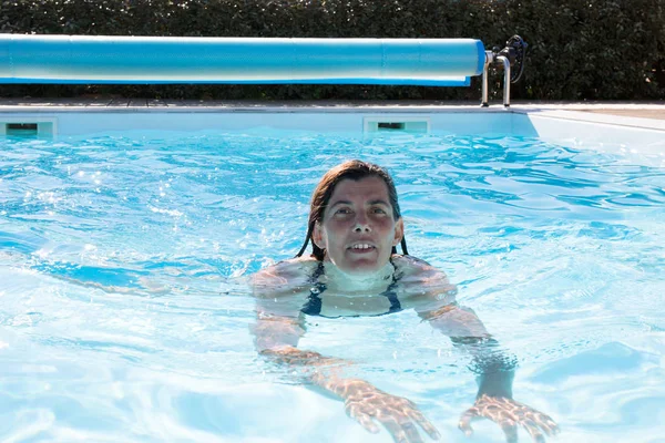 Donna che nuota in piscina il giorno d'estate — Foto Stock