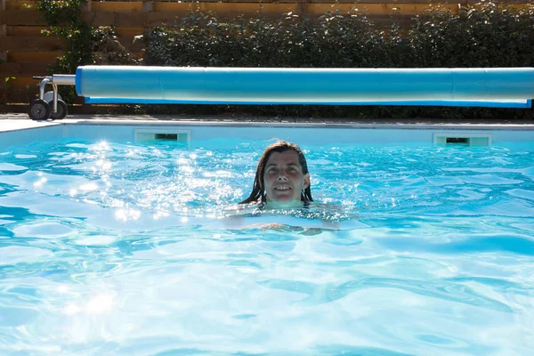 Una donna che nuota nella piscina blu — Foto Stock