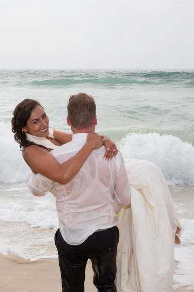 Αγαπώντας το ζευγάρι σε γάμο φόρεμα πηγαίνοντας προς τη θάλασσα για κολύμπι με ρούχα — Φωτογραφία Αρχείου
