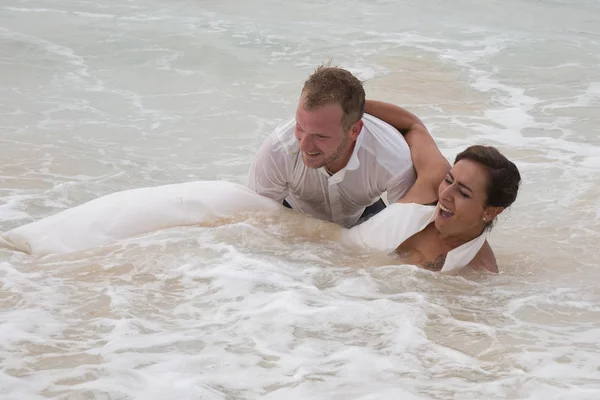 Η νύφη και ο γαμπρός έχουν διασκέδαση σε γάμο στην παραλία άμμου στον ωκεανό — Φωτογραφία Αρχείου