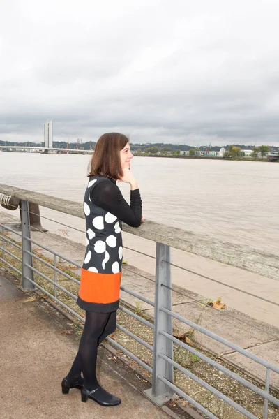 Charmig kvinna i en stad nära en flod, som tittar — Stockfoto