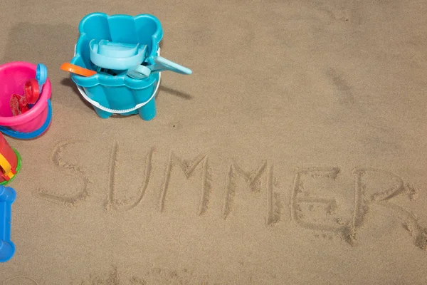 Escrita de verão em areia e brinquedos de plástico para crianças para brincar nas férias de praia — Fotografia de Stock