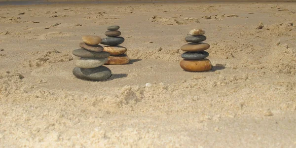 Несколько груд пирамидального камня на песке пляжа — стоковое фото