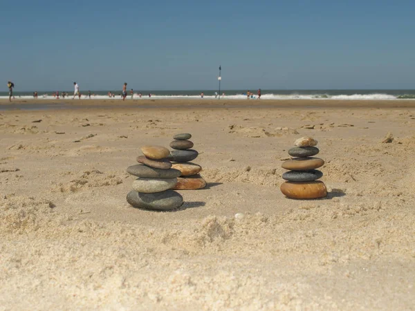 Drie piramide van steen of kiezels op het zand voor de zee of de Oceaan — Stockfoto