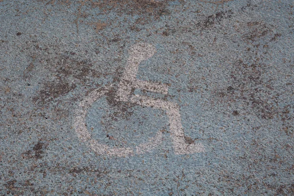 Старий пофарбований логотип на підлозі парковки, зарезервований для інвалідів — стокове фото