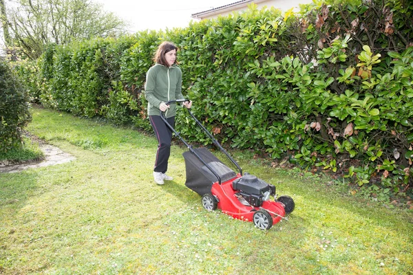 Mulher passa o cortador de grama nos fins de semana em seu jardim — Fotografia de Stock
