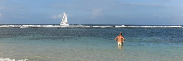 Člověk využívá této karibské dovolené koupat a dívat se lodě jít dál — Stock fotografie