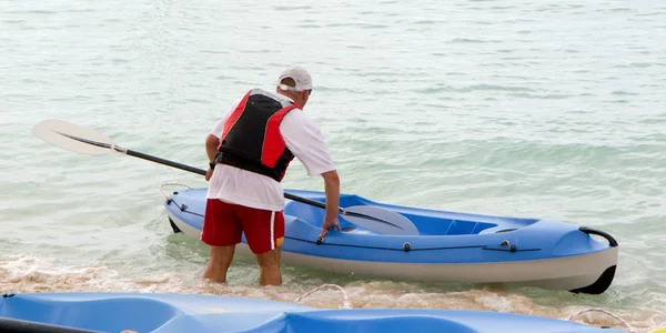 熱帯の海で青いカヌーを持つ男 — ストック写真