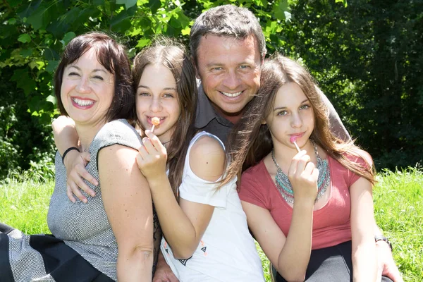 Mutlu aile baba ve bir anne ve iki genç İkizler parkta yeme lolipop — Stok fotoğraf