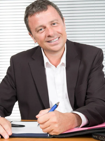 Middle-aged man signs a contract at his office Stock Picture