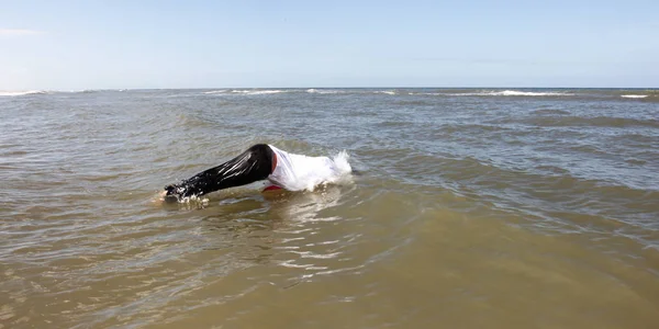 Hombre en pantalones y camisa sumergiéndose en el océano — Foto de Stock