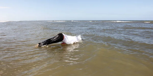 Man in pants and shirt diving into the ocean — Stock Photo, Image