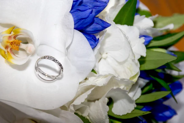 Blue and white flowers and wedding rings on a board — Stock Photo, Image