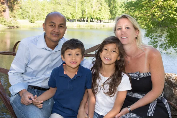 Famille assise au bord de l'eau avec un père d'origine indienne et une mère blonde aux yeux bleus Caucasien — Photo