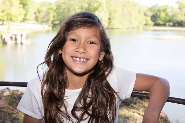 Menina dá um belo sorriso junto ao lago — Fotografia de Stock