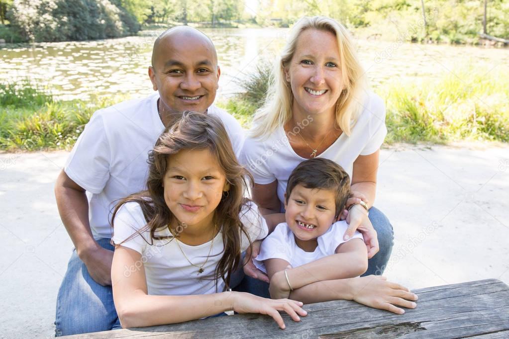 multiracial family sitting in the park in the grass